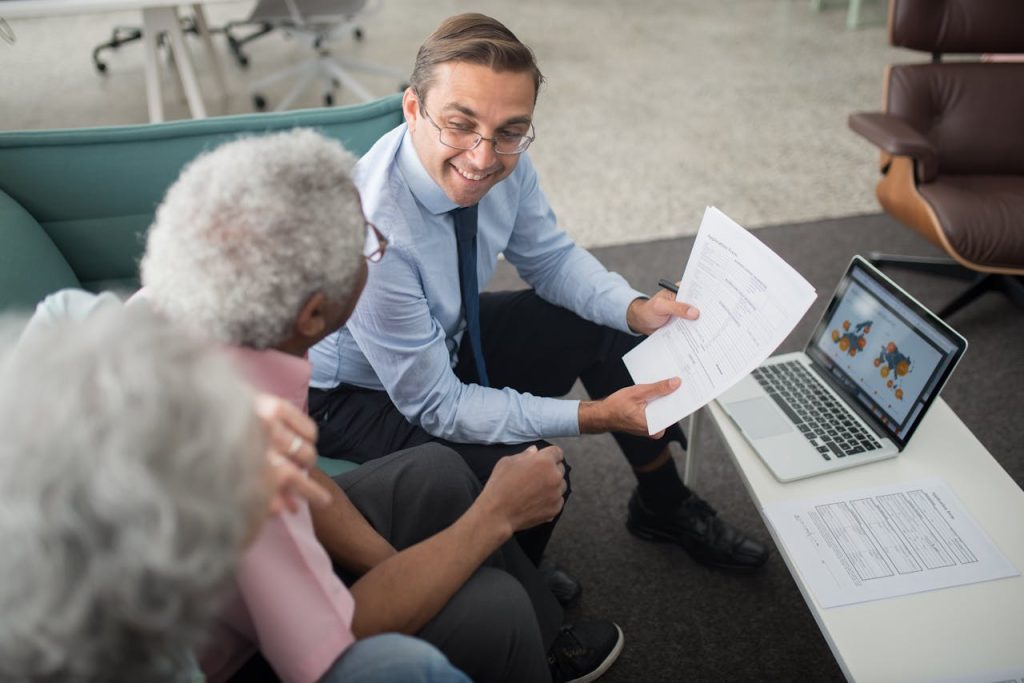 an-agent-showing-documents-to-an-elderly-man-8441811 Financial advisor discussing documents with senior clients in an office setting, showcasing a collaborative consulting session.